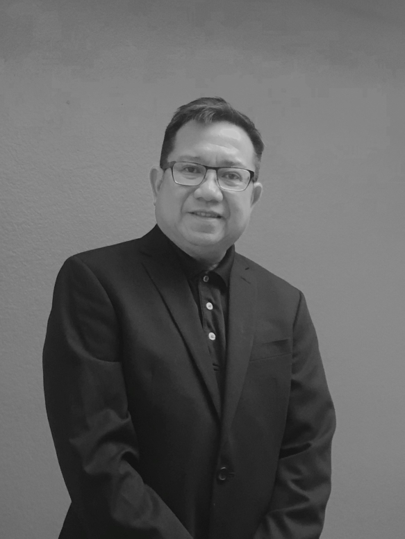 Grayscaled upper half portrait of Dennis Gamalinda in a dark suit